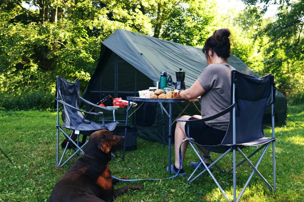 Camperin mit Hund am Campingtisch im Naturcamp