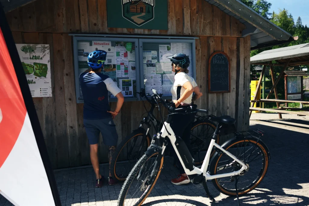Radfahrer mit E-Bikes an der Infotafel am Naturcamp