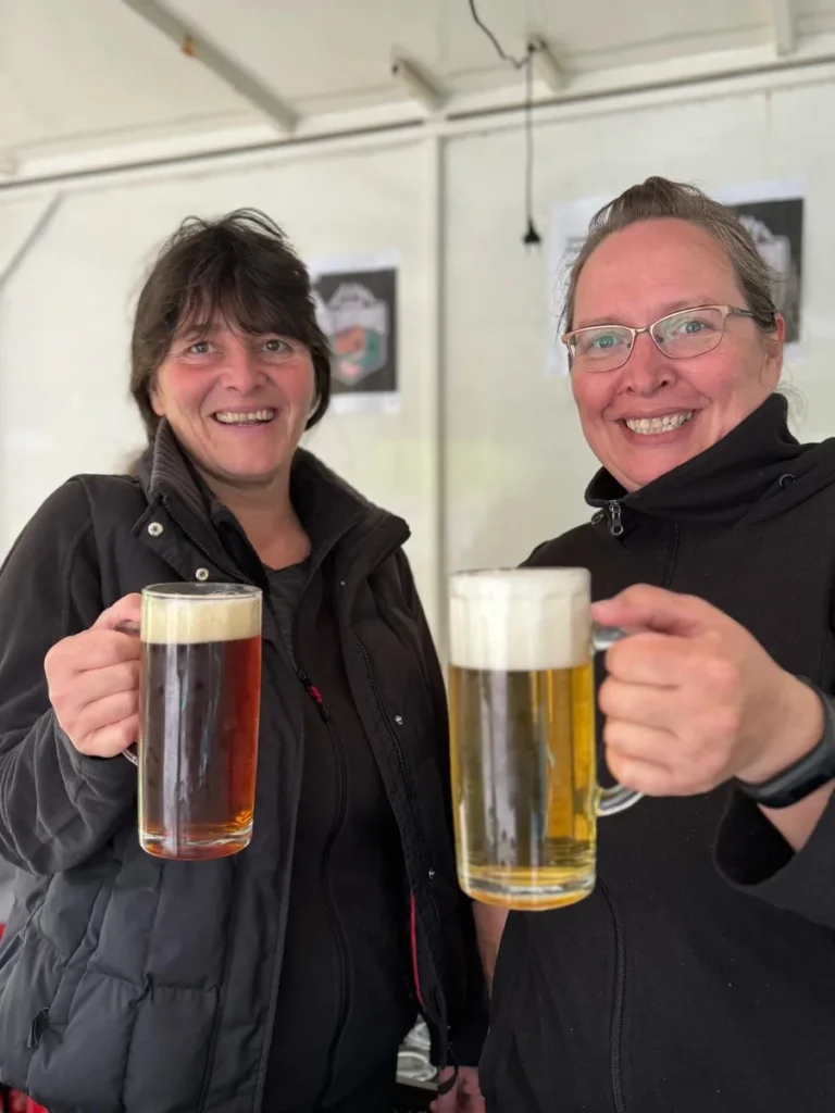 Zwei Mitarbeiterinnen vom Naturcamp Meyersgrund stoßen lachend mit Bier an